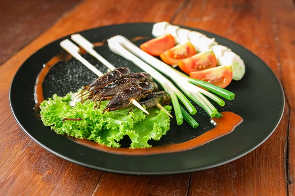 Grillons frits, nourriture pour insectes dans la brochette sur une assiette brune. Clos — Photo