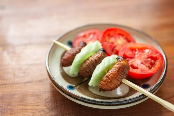 Fried Worm, Insect food in the skewer with wooden table backgrou