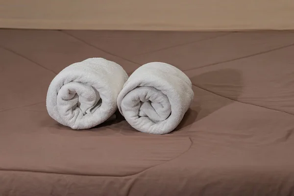 White bath towels roll on a bed in the hotel suite.