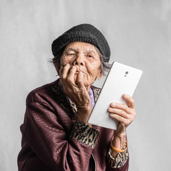 Retrato de una mujer mayor confundida con la tableta en traje vintage Imágenes de stock libres de derechos