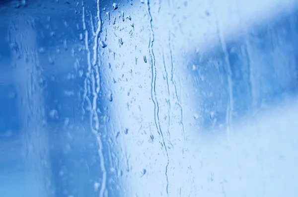 Gotas de lluvia en el vidrio de la ventana, tonificado azul, cambio de inclinación — Foto de Stock