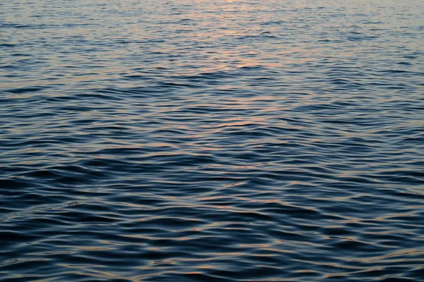 Textura de agua de mar al atardecer, colores azul y naranja del sendero del sol — Foto de Stock