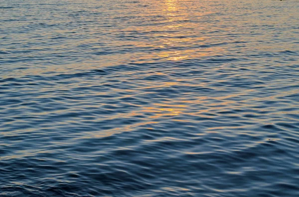 Texture di acqua di mare al tramonto, colori blu e arancio del percorso del sole — Foto Stock