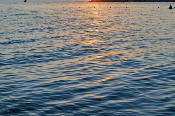 Texture di acqua di mare al tramonto, colori blu e arancio del percorso del sole — Foto Stock