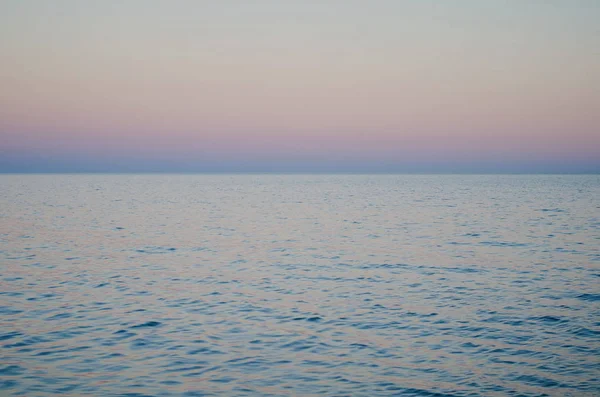 Capa marinha de água e horizonte após o pôr do sol, cores azul e rosa — Fotografia de Stock