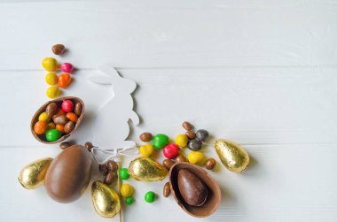 Çikolata yumurta ve şeker Beyaz ahşap zemin üzerinde beyaz Paskalya tavşanı