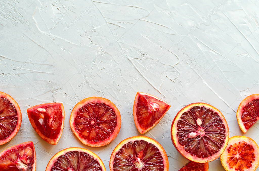 Closeup of red Sicilian blood (bloody) oranges - cut and sliced, ripe and tasty with copy space for your text, gray cement background