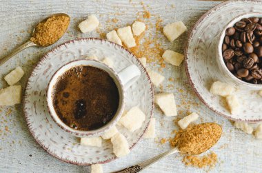 Küçük bir fincan kahverengi şeker kamışı ve gri ahşap zemin üzerine Lump & şekerli kahve  