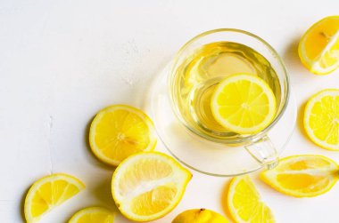 Dilimleri o beyaz zemin üzerine saydam bir fincan limon çayı