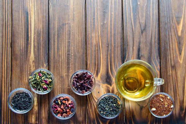 Selection of assorted teas in transparent little bowls on natural wooden background — Stock Photo, Image