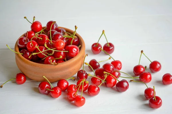 Tigela de cerâmica marrom de cerejas frescas e saborosas em fundo branco de madeira — Fotografia de Stock