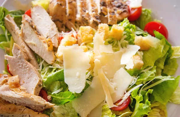 Caesar salad with chicken, selection of cheese, and cherry tomatoes. Top view