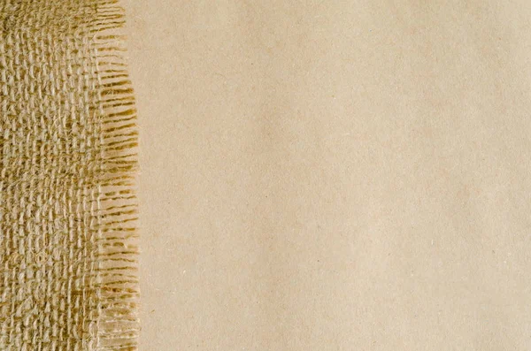 Border of canvas burlap sackcloth on background of craft packing parchment paper