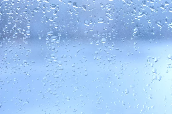 Regentropfen auf sauberes blaues Fensterglas — Stockfoto
