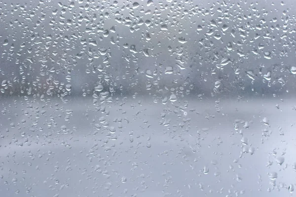 Regendruppels op zuiver blauw raamglas — Stockfoto