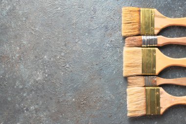 Gri çimento arka planda boya fırçaları, üst görünümde resim çizme araçları