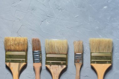 Gri çimento arka planda boya fırçaları, üst görünümde resim çizme araçları