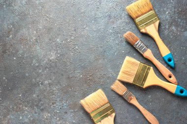 Gri çimento arka planda boya fırçaları, üst görünümde resim çizme araçları