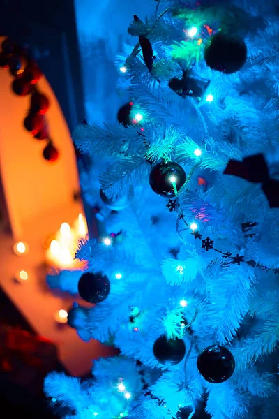 Árvore de Natal iluminada ao lado de uma lareira. Luzes de Natal brilhantes no escuro. Noite de Natal de Ano Novo. Véspera de Natal. Arranjo interior . — Fotografia de Stock