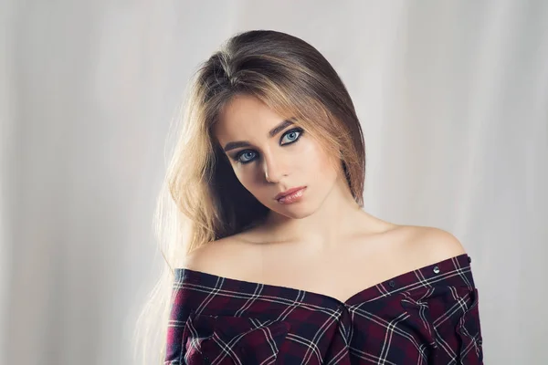 Portrait de haute qualité d'une fille sur un fond clair. Portrait de studio féminin. Belle dame naturelle. Maquillage lumineux. Maquillage des yeux fumés. Cheveux bruns. Fille en chemise à carreaux . — Photo