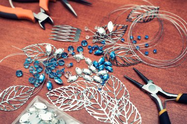 Tel, rhinestones ve kristalleri ile takı oluşturma işlemi. Masanın üzerinde çalışma araçları. El yapımı takılar. Ev yapımı ürünler. Üretim süreci içinde gelin bir tarak.