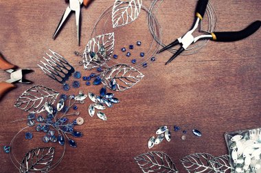 Tel, rhinestones ve kristalleri ile takı oluşturma işlemi. Masanın üzerinde çalışma araçları. El yapımı takılar. Üretim süreci içinde gelin bir tarak.