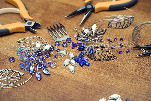 El proceso de creación de joyas con alambre, diamantes de imitación y cristales. Herramientas de trabajo sobre la mesa. Joyería hecha a mano. Un peine nupcial en el proceso de fabricación . — Foto de Stock