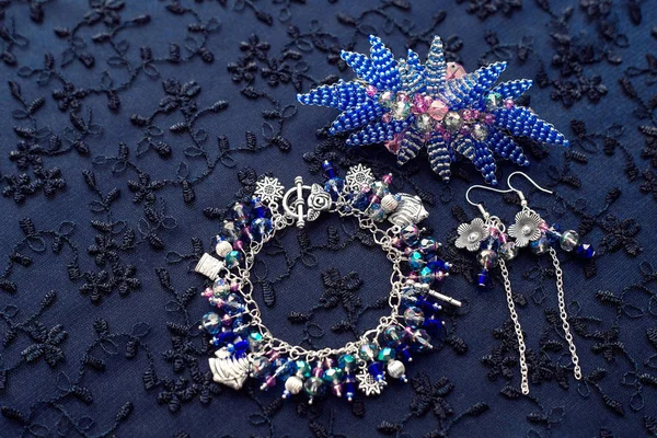 Set di gioielli. Bracciale con pendenti e perline in vetro e metallo. Sfondo strutturato con gioielli. Orecchini e fiori di perline . — Foto Stock