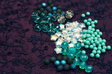 Turkuaz boncuklar tekstilin üzerine saçılmış. Yaratıcı hobiler için fikirler. El yapımı mücevherler için cam taşlar.