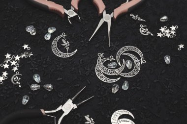 Tel, metal kolyeler ve kristalleri ile takı oluşturma işlemi. Masanın üzerinde çalışma araçları. El yapımı takılar. Üretim süreci içinde gelin takılar.