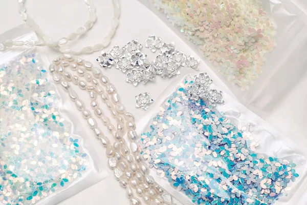 Materiali per lavori creativi su sfondo bianco. Perle d'avorio e paillettes azzurre — Foto Stock