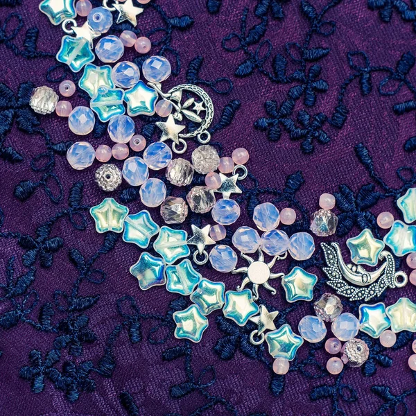 银月亮和星星吊坠和粉红色猫眼石珠刺绣织物，时尚背景 — 图库照片