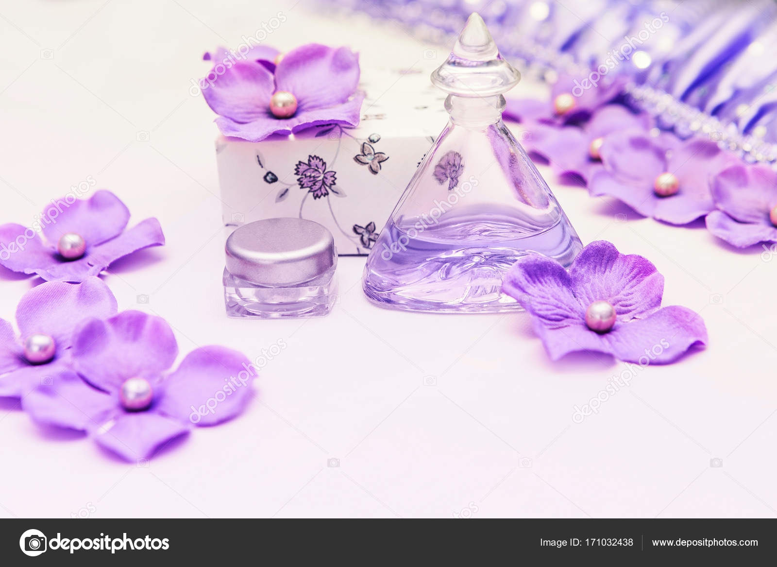 Perfume Bottle With A Box And Some Purple And Pink Decorations On