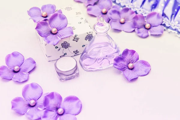 Bouteille de parfum avec une boîte et quelques décorations violettes et roses sur fond blanc, cosmétiques femme — Photo