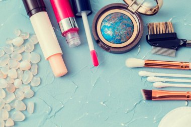 Turkuaz arka plan, dudak kremi, göz farı, makyaj fırçası, yüz bakımı için profesyonel cilt bakımı ürünleri.