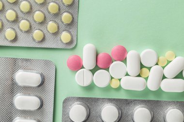 Eczane ilaçları, yeşil arka planda su toplayan tabletler ağrı kesiciler ve diğer tıbbi ürünler.