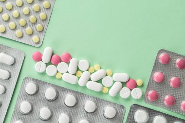 Eczane ilaçları, yeşil arka planda su toplayan tabletler ağrı kesiciler ve diğer tıbbi ürünler.