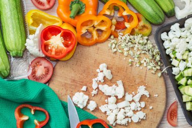 Kesme tahtasında taze sebzeler, biber dilimleri, kabak, domates ve sebze pişirmek için karnabahar.