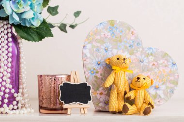 Bir çift tekstil ayısı, bir vazo çiçek, bir şamdan ve yatak odasındaki şifonyerin üzerindeki diğer güzel şeyler.