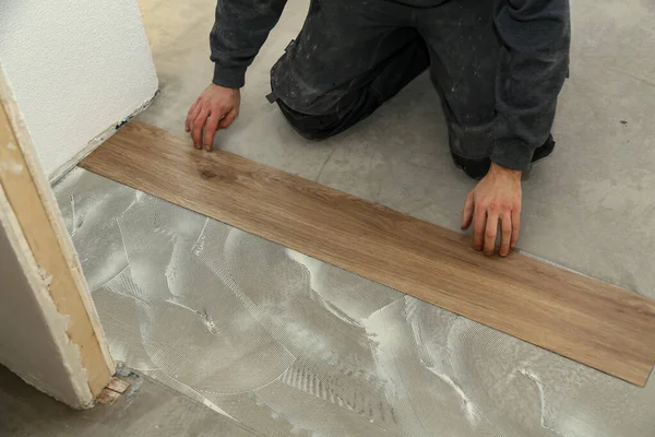 The worker installing new vinyl tile floor — Stock Photo, Image