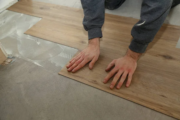 The worker installing new vinyl tile floor — Stock Photo, Image