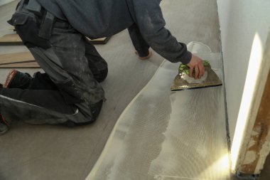 Yeni vinil döşeme döşeyen işçi