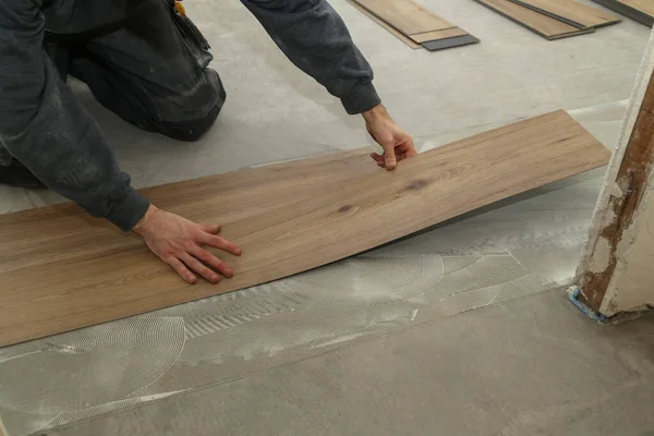 The worker installing new vinyl tile floor — Stock Photo, Image