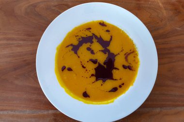 Beyaz tabakta balkabağı kremalı çorba.