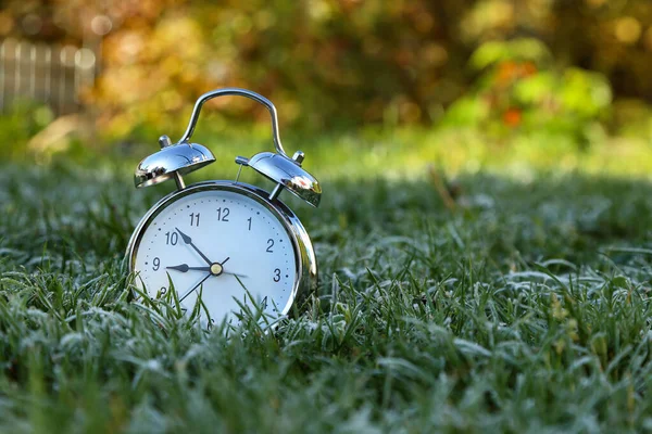 目覚まし時計は霜で覆われた草の中にあります — ストック写真