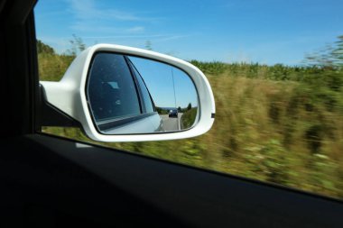 Arabanın yan aynasında yol manzarası.