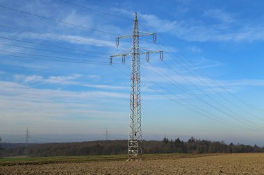 Mavi gökyüzüne karşı elektrik direkleriyle manzara