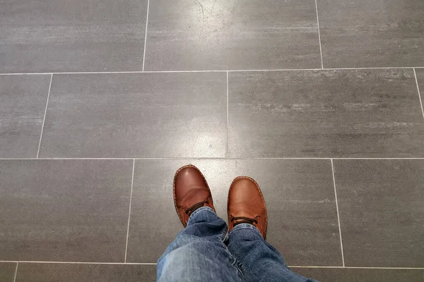 ジーンズの足とタイルの床の背景にある赤いブーツ — ストック写真