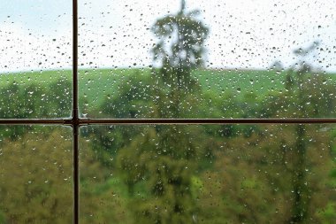 Rainy weather behind wet glass of a house window. clipart