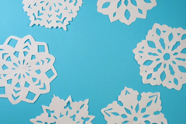 Schöne dekorative Schneeflocken aus Papier auf blauem Hintergrund geschnitten. Foto für Weihnachten und Neujahr — Stockfoto